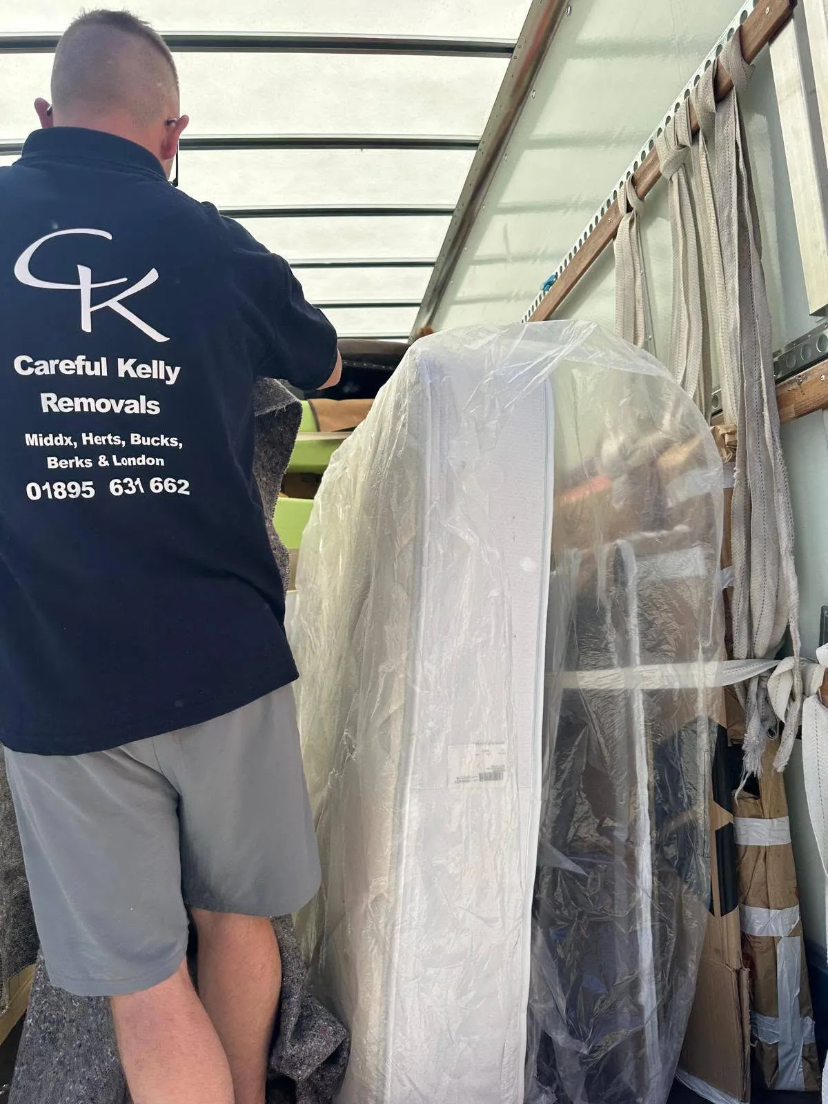 Careful Kelly Removals crew member carefully loading a wrapped mattress into a removal van