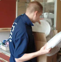Careful Kelly Removals crew member packing crockery into a box