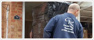 Careful Kelly Removals crew member carrying a wrapped item into a West London home
